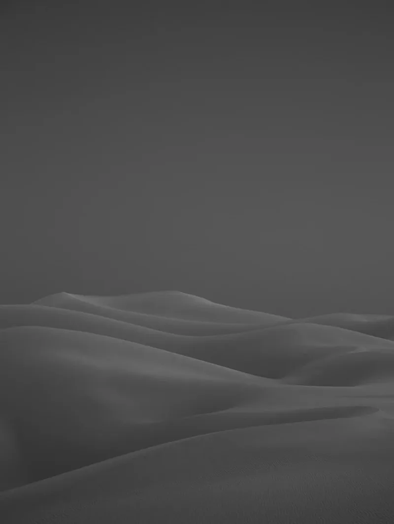 Imperial Dunes I — black-and-white portrait-format photograph of sensuous sand dune curves receding under a dark sky, Imperial Sand Dunes, California. Medium format film by Alex Hoerner.